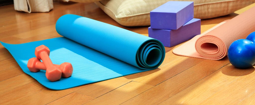 Yoga mat and exercise weights on wooden floor - Fizyoterapist Dr. Şule OKUR DÜNDAR